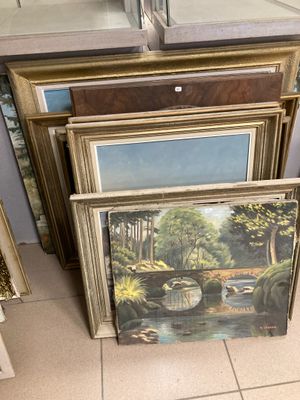 beaucoup d'œuvres d'art encadrées posées par terre dans un magasin
