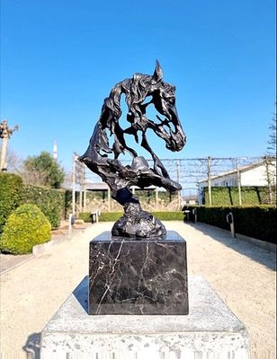 a statue of a horse on a pedestal in the middle of a garden