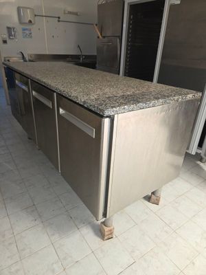 îlot de cuisine en acier inoxydable avec plan de travail en granit dans une cuisine professionnelle