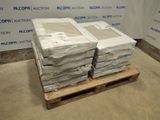 Des cartons contenant des matelas sont empilés sur une palette devant un mur