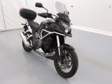 une moto noire garée dans une pièce aux murs blancs