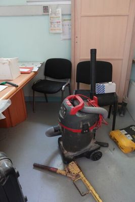 une pièce équipée d'un bureau, d'une chaise et d'un aspirateur