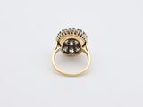 a close up of a gold ring with a black and white diamond center