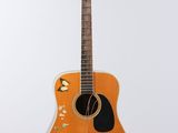 an orange guitar with flowers painted on it hanging from a white wall