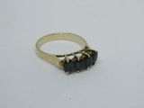 une bague en or ornée de trois pierres noires