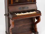 Un vieux piano est posé sur un support sur lequel est accrochée une pancarte