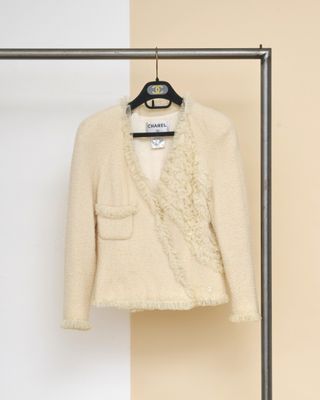 une veste beige suspendue à un cintre devant un mur beige