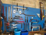 many tools hanging on a blue wall in a garage
