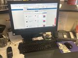 un bureau sur lequel se trouvent un ordinateur, un clavier, un téléphone et d'autres objets