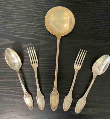 cinq cuillères en argent et deux cuillères en argent posées sur une table noire