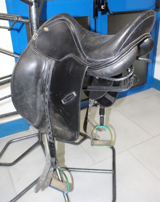 a black saddle on a stand in a blue room