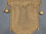 un sac à main en maille dorée, orné de clochettes qui pendent de tous côtés