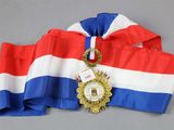 a red, white, and blue ribbon with a gold medal on it