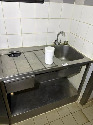 a sink and a trash can in a public restroom