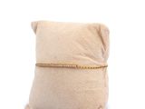 beige pillow with a gold chain on top of it on a white background
