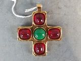 une croix en or ornée de pierres rouges et vertes