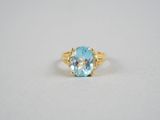 un gros plan d'une bague sertie d'une topaze bleue sur une surface blanche