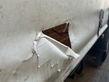 a white truck that has been vandalized and has a hole in the side of it