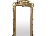 un miroir à cadre doré orné d'un motif décoratif dans sa partie supérieure
