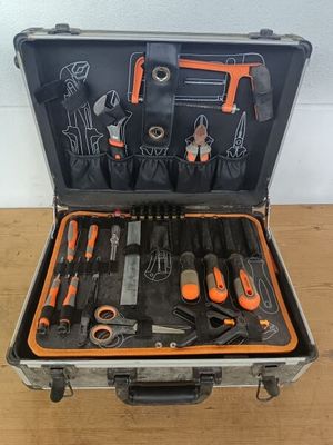 une trousse à outils dans un coffret posé sur une table en bois