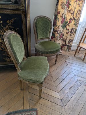 two green chairs sitting in a room with a wooden floor