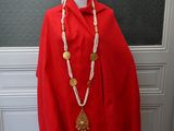 a mannequin wearing a red shawl and a necklace with gold coins