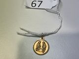 une pièce d'or sur laquelle est représenté un oiseau, suspendue à un fil