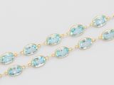 a close up of a gold chain with blue topaz beads