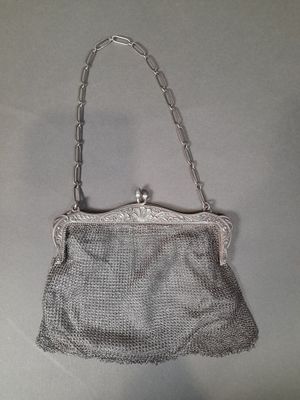 a silver purse with a chain handle hanging from it ' s side