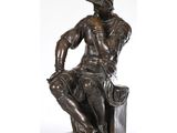 une statue représentant un homme assis sur un bloc de bois