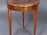 une petite table avec un plateau circulaire et un piètement en bois