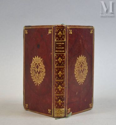 un livre rouge orné de motifs dorés, posé sur une surface blanche