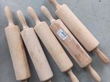 four wooden rolling pins are lined up on a table