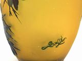 a yellow vase with a bird on it on a white surface