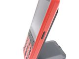 a red cell phone sitting on a stand on a white surface