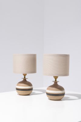 two wooden lamps on a white table with a beige shade
