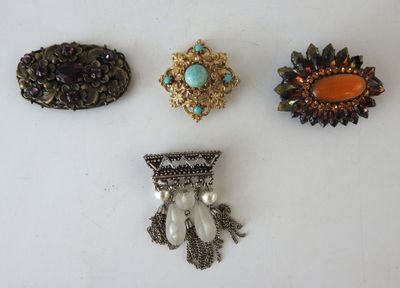 three brooches and a brooch are sitting on a white surface
