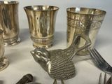 silver cups and spoons and a bird on a table
