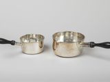 pair of silverplated saucepans with black handles