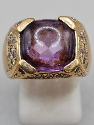 a close up of a ring with a purple stone surrounded by diamonds