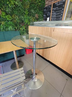 une table avec un plateau en verre et une chaise placée devant un mur vert