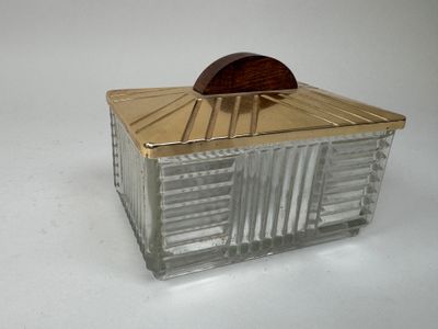 une boîte en verre avec un couvercle en bois posée sur une surface blanche