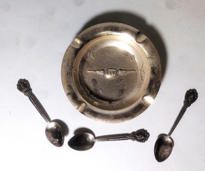 un cendrier en argent avec des cuillères et un repose-cuillères posé sur une table