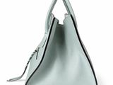 a green handbag on a white background with a black handle