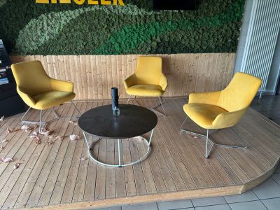 trois chaises jaunes et une table devant un mur vert