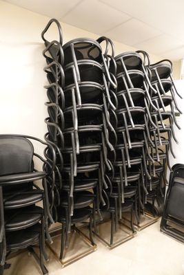 rows of black chairs stacked on top of each other in a room
