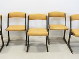 quatre chaises jaunes sont alignées contre un mur blanc