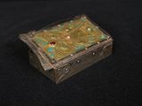 an old silver box with a green and gold design on it