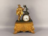 une horloge en or surmontée d'une statue représentant un homme et une femme
