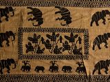 a black and white picture of elephants on a tan cloth